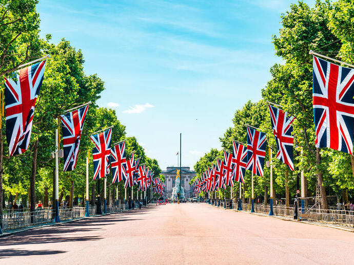 Avenue of trees down to a palace with flags hung either side