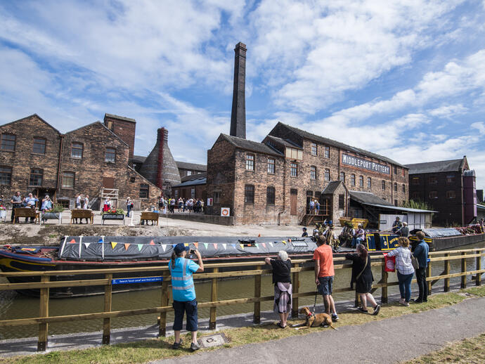 A group of people looking across the Trent and Mersey Canal at several historic buildings in Stoke