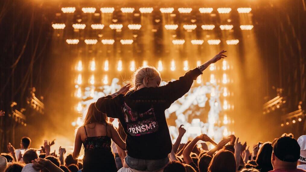 Girl sitting on the shoulders of a guy in the crowd at TRNSMT festival