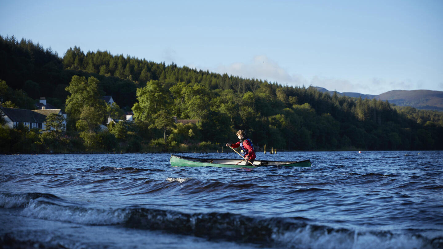 Hombre practicando piragüismo en un lago en un día soleado y despejado.
