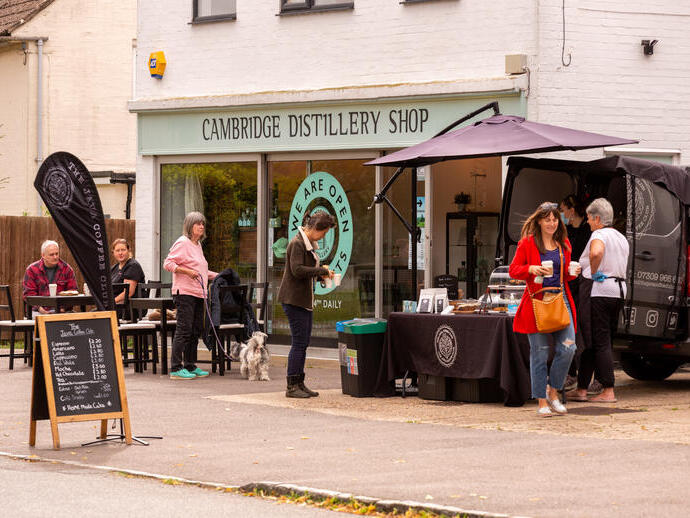 Persone fuori dal negozio con insegna: Cambridge Distillery Shop