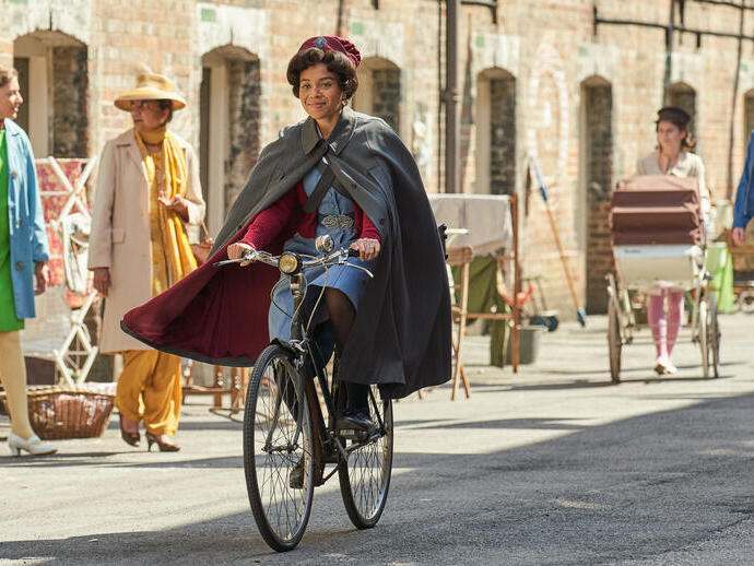 Woman dressed up in 1950's nurse costume riding a bike