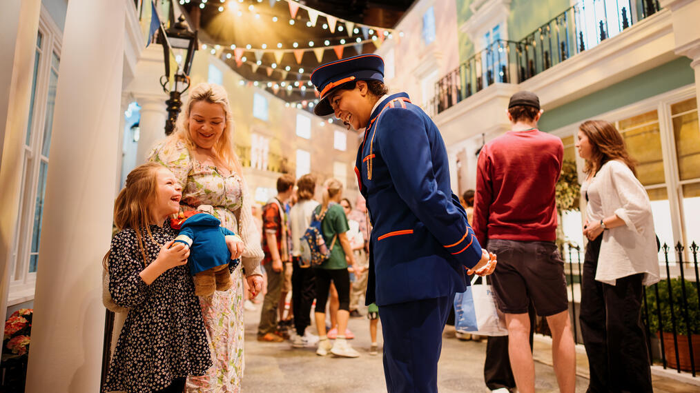 Character actors talking to a young child on the set of a stage.