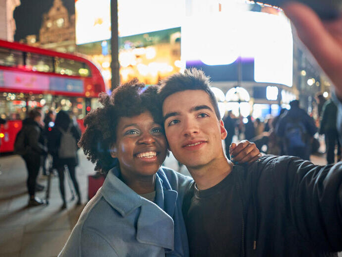 Couple taking a selfie on a phone in a busy city