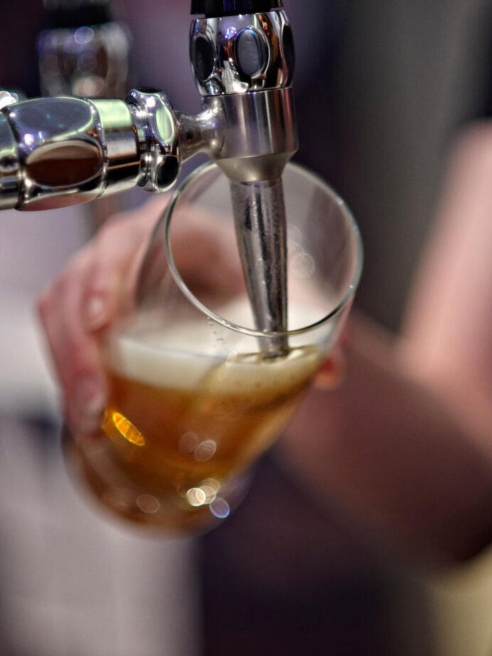 A person pouring a beer from a tapped keg