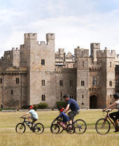 Family cycling past castle in North East England