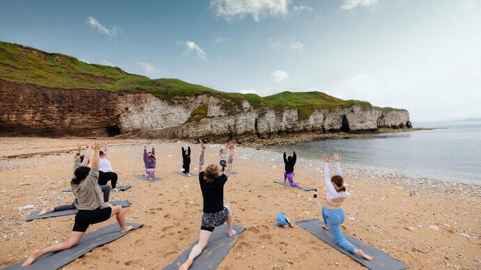 Un grupo de personas practicando yoga en la playa