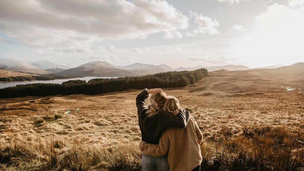 Deux amis s'étreignant en contemplant la vallée, le lac et les montagnes