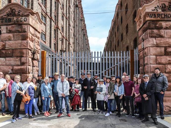 A Peaky Blinders tour group posing outside an industrial warehouse in Liverpool