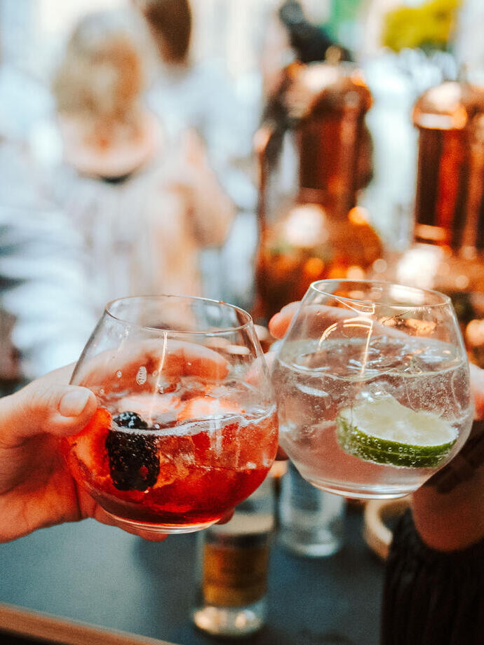 Two people toast cocktail drinks