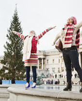 Women standing on the rim of a fountain in a city square at Christmas