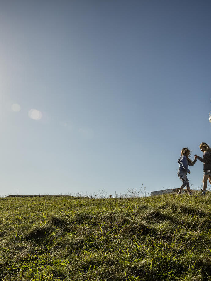 Two children playing in open space by a lighthouse