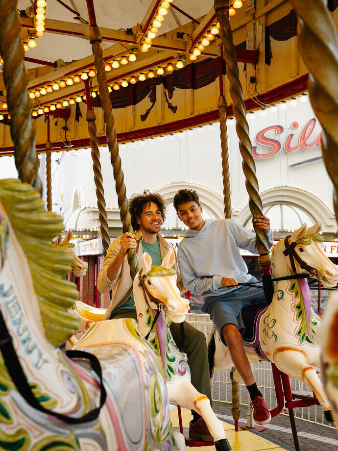 A father and son ride on a Carousel in an amusement park