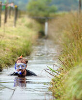 A bog snorkeler wading through a canal
