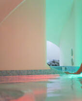 Woman relaxing in an indoor spa pool with curved architectural arches and soft ambient lighting.