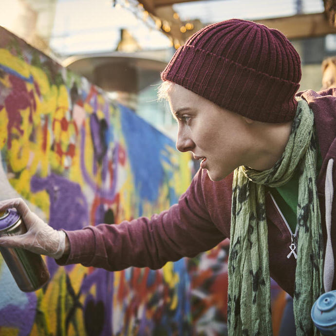 Femme utilisant une bombe de peinture pour créer une fresque murale