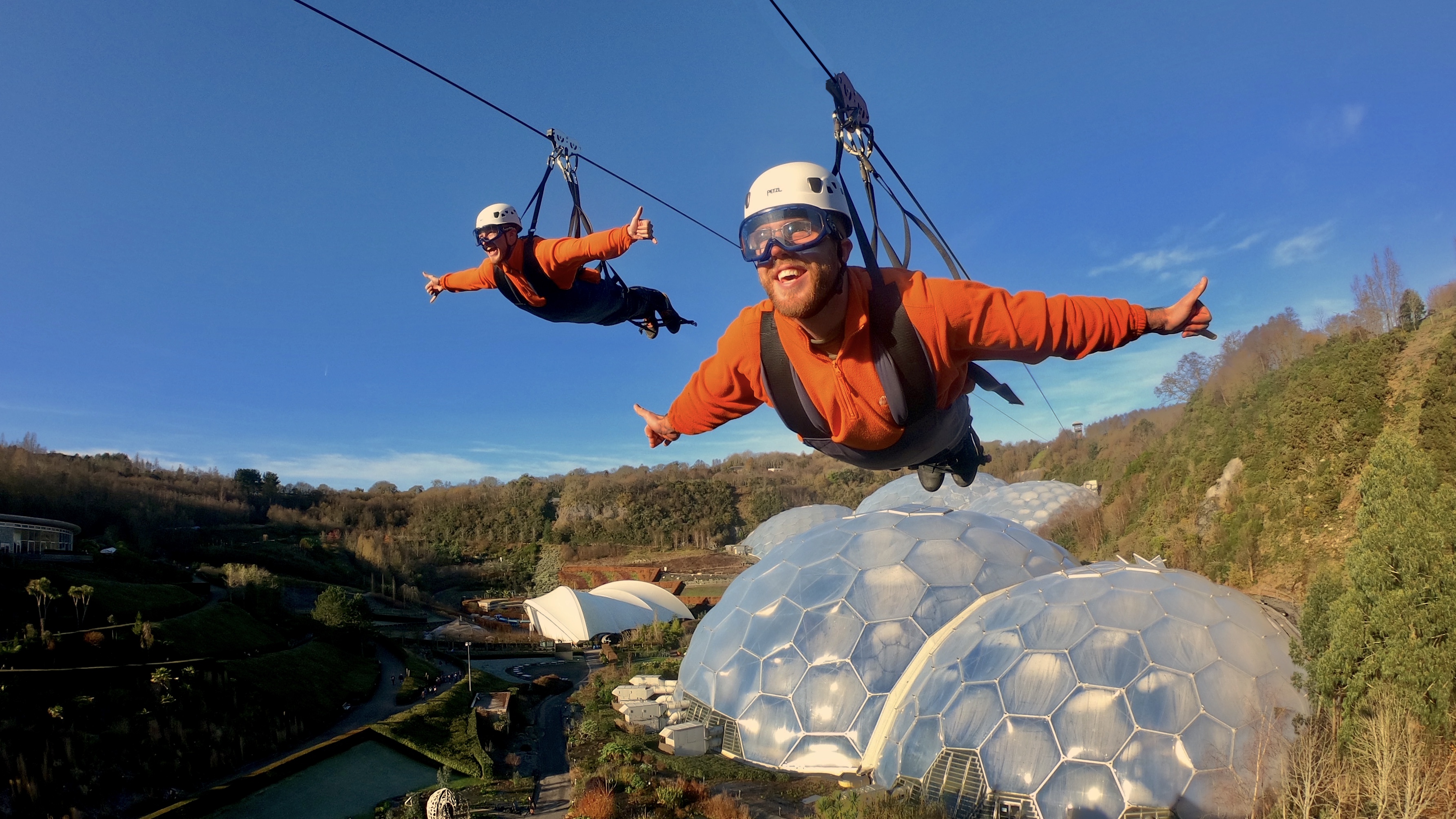 Two people suspended on a zipline above the Eden Project