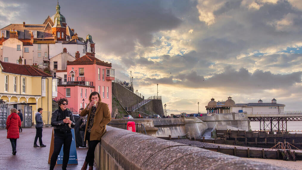 Groups of people stood on the promenade looking out on Cromer Beach