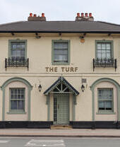 Entrance to a British pub with a sign that reads 'The Turf'.