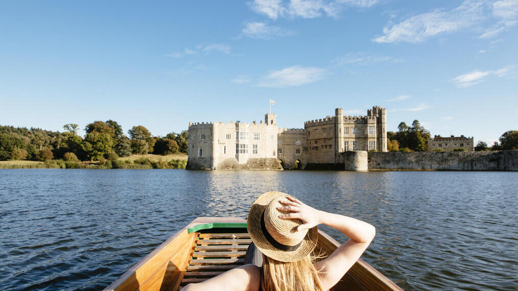 Woman in a punt on the moat looking towards castle