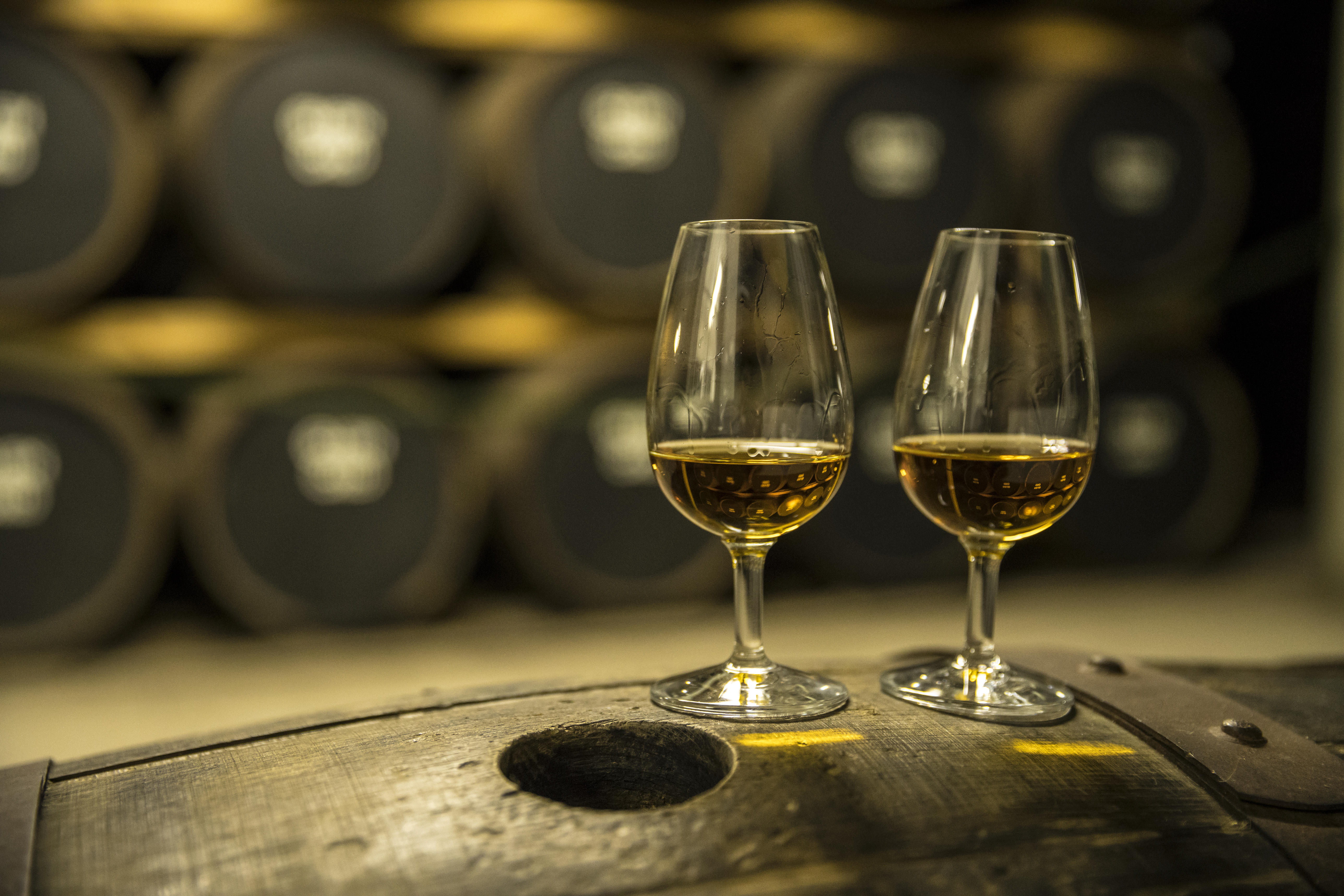Two glasses of whisky on an oak barrel