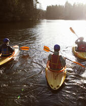 Kayakers rowing together in a group along a river.
