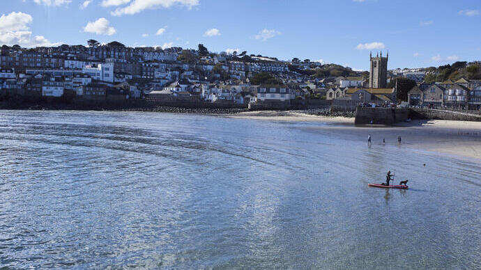 Distant view of town and harbour with people in the sea