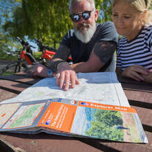 Two people sat at a picnic table, looking at an Ordinance Survey Explorer map of the National Forest.