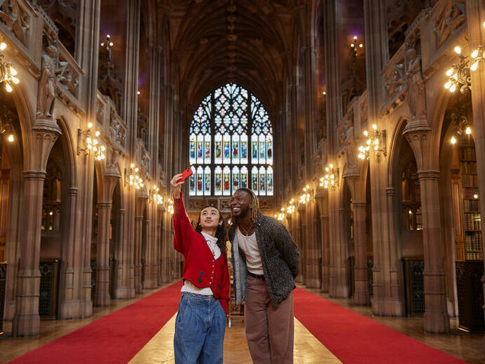 Due uomini che si scattano un selfie all'interno di una grande biblioteca.