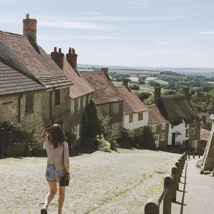 Mujer caminando por una empinada calle empedrada de un pueblo en verano
