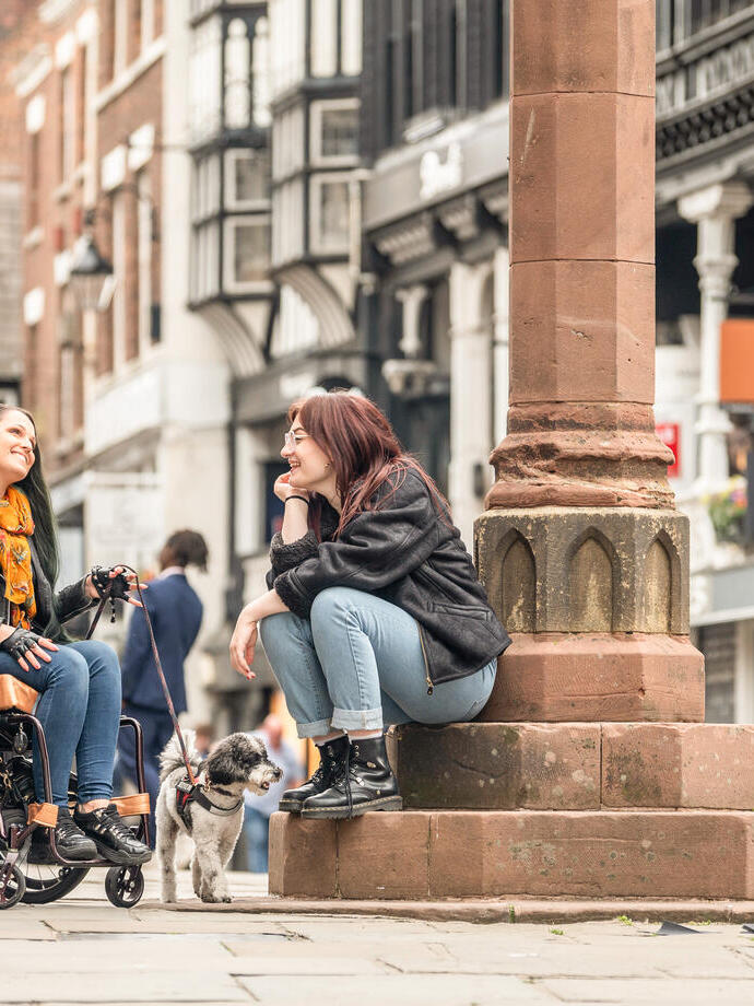 Two women sit talking together in a town centre