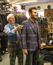 Man being measured by a tailor for a jacket in a traditional tailor's shop