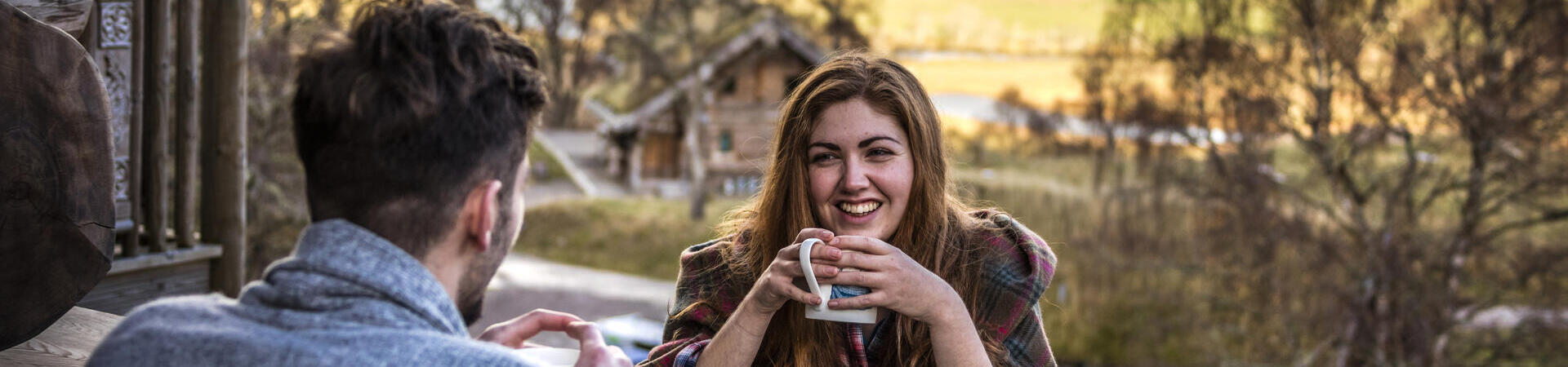 Couple sat at a wooden table drinking tea in a valley