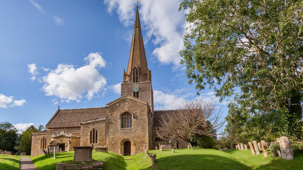 Una chiesa parrocchiale con le sue lapidi e i giardini antistanti.