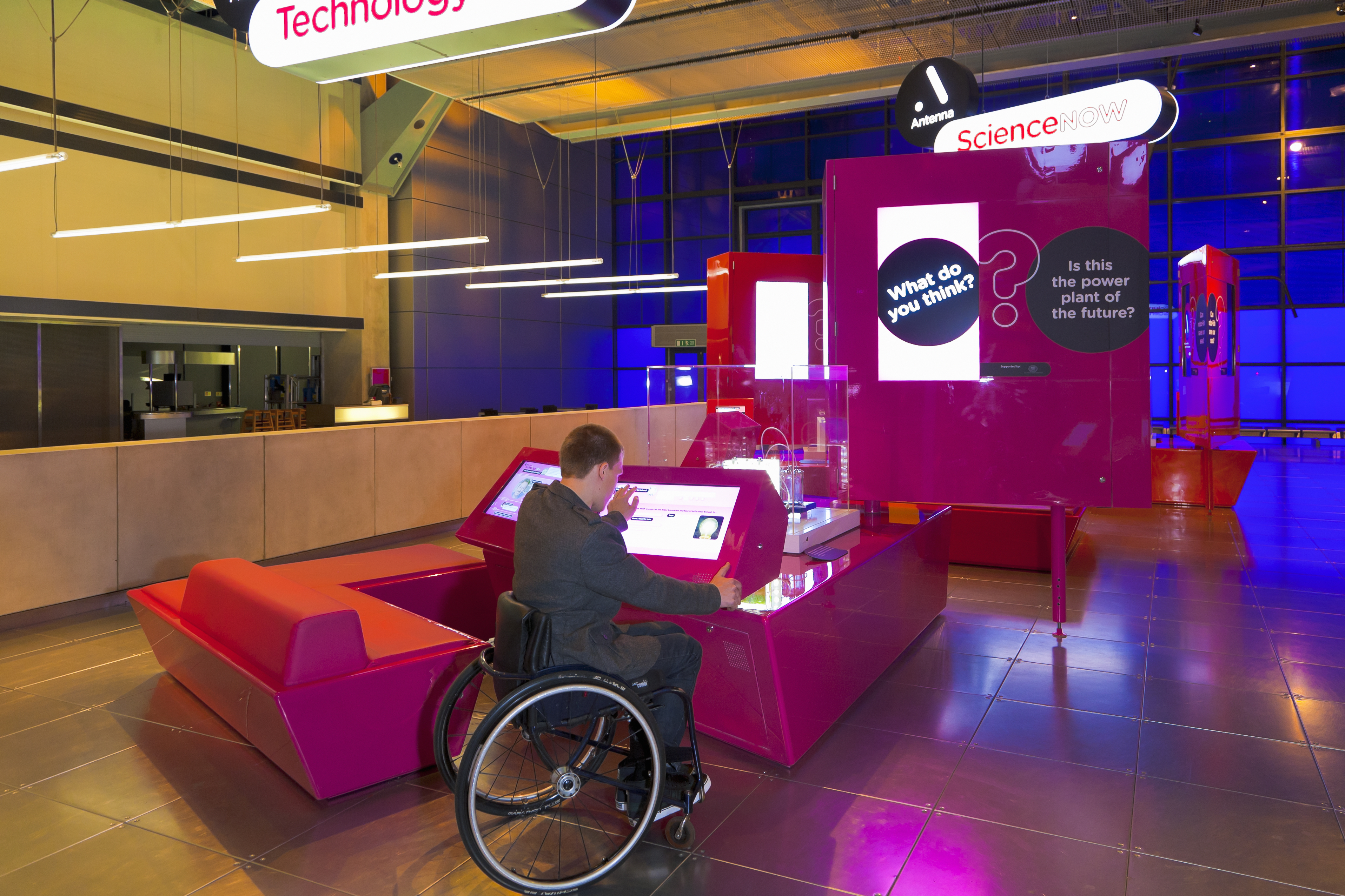 Homme en fauteuil roulant utilisant un écran interactif dans un musée