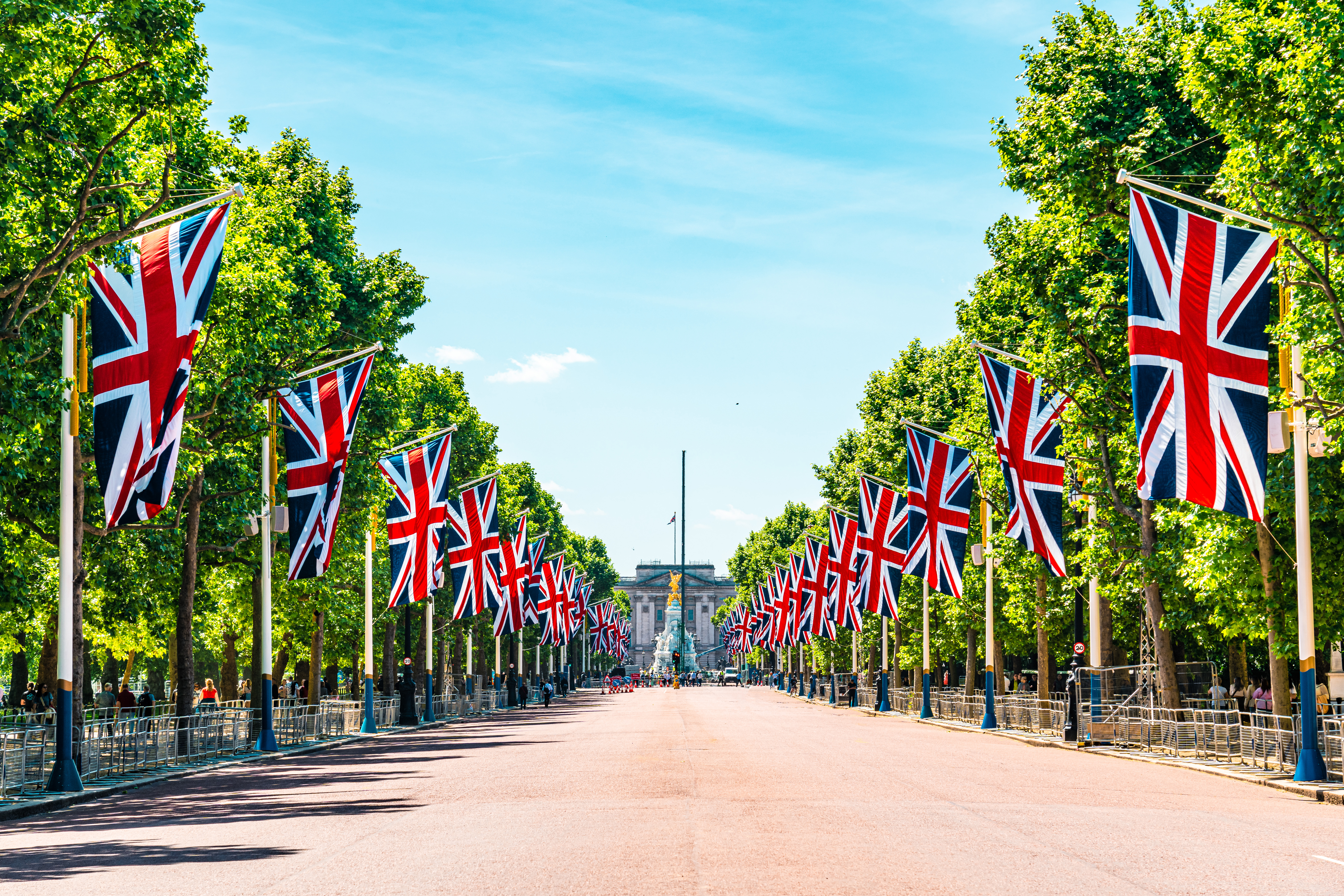 Avenue of trees down to a palace with flags hung either side