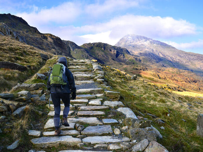 Trekker hiking up a mountainous cobble stoned path through a barren mountain range