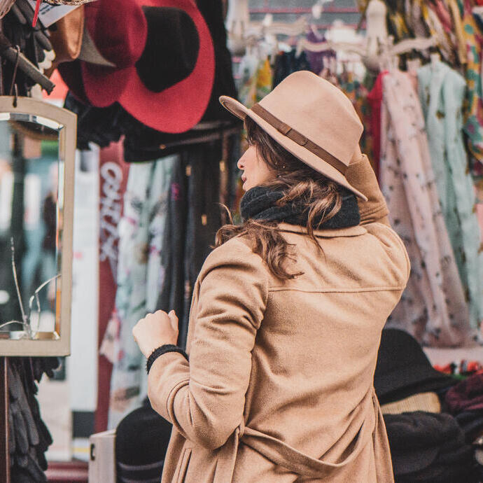 Eine Frau probiert Hüte an einem Stand auf dem Portobello Road Market in London