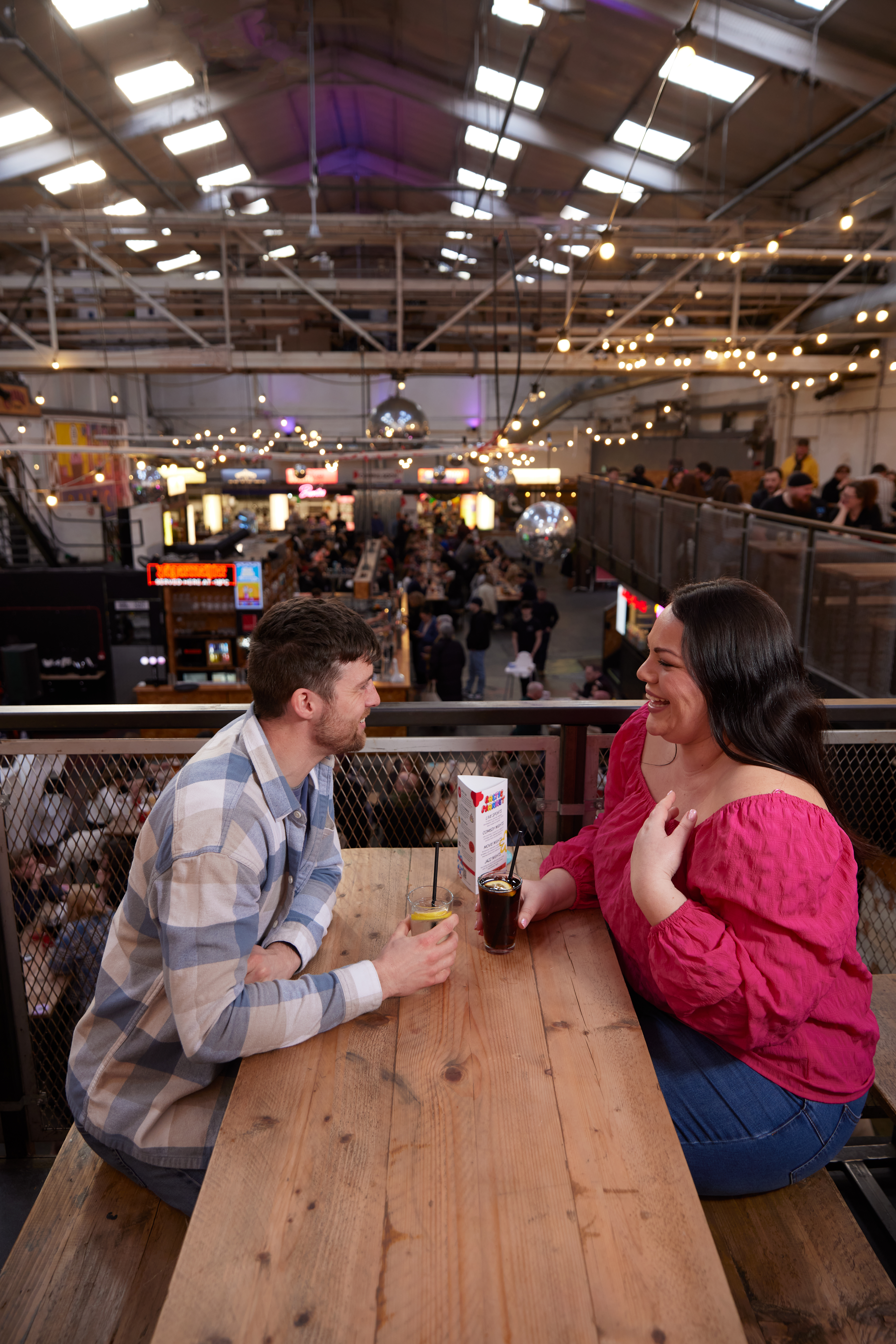 A man and a woman enjoying a drink at a local food hall.