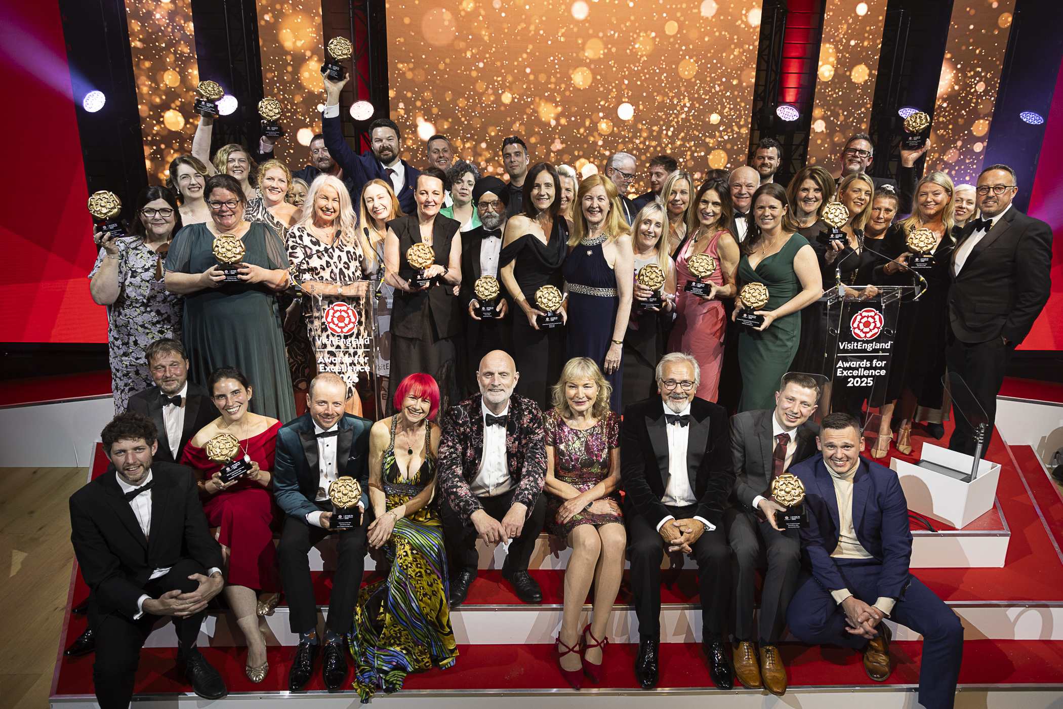 A group of winners on stage holding their awards at a gala ceremony.