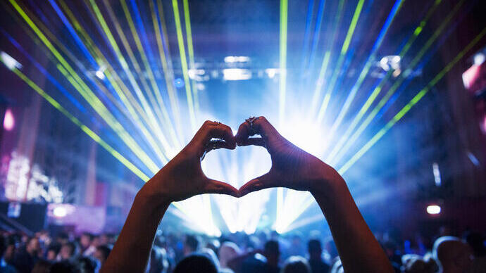 Woman making heart shape with hands at a music event