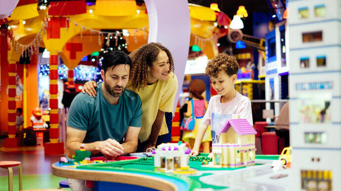 Mother, father and son laughing whilst playing with Lego