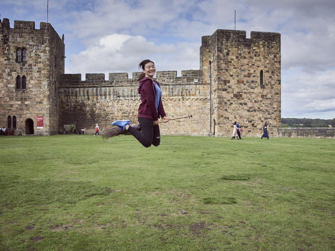 Femme sur un balai devant un château