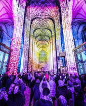 Grupo de personas mirando y fotografiando un espectáculo de luces en una catedral
