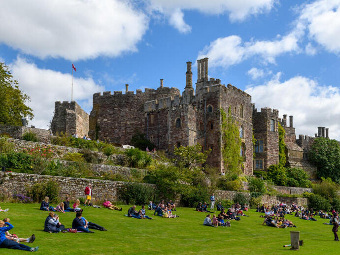 Crowds enjoying a sunny afternoon on the grounds of a castle.