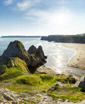 Coastline with a sandy beach and rocky peninsula.