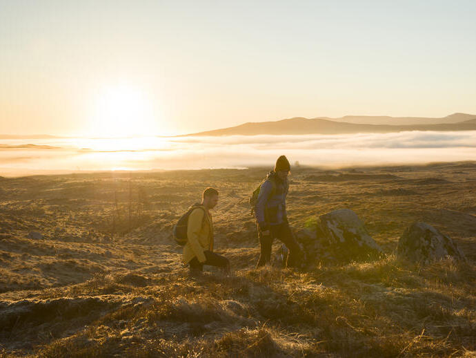 رجلان يتنزهان في المرتفعات عند غروب الشمس. أشعة الشمس المتدفقة