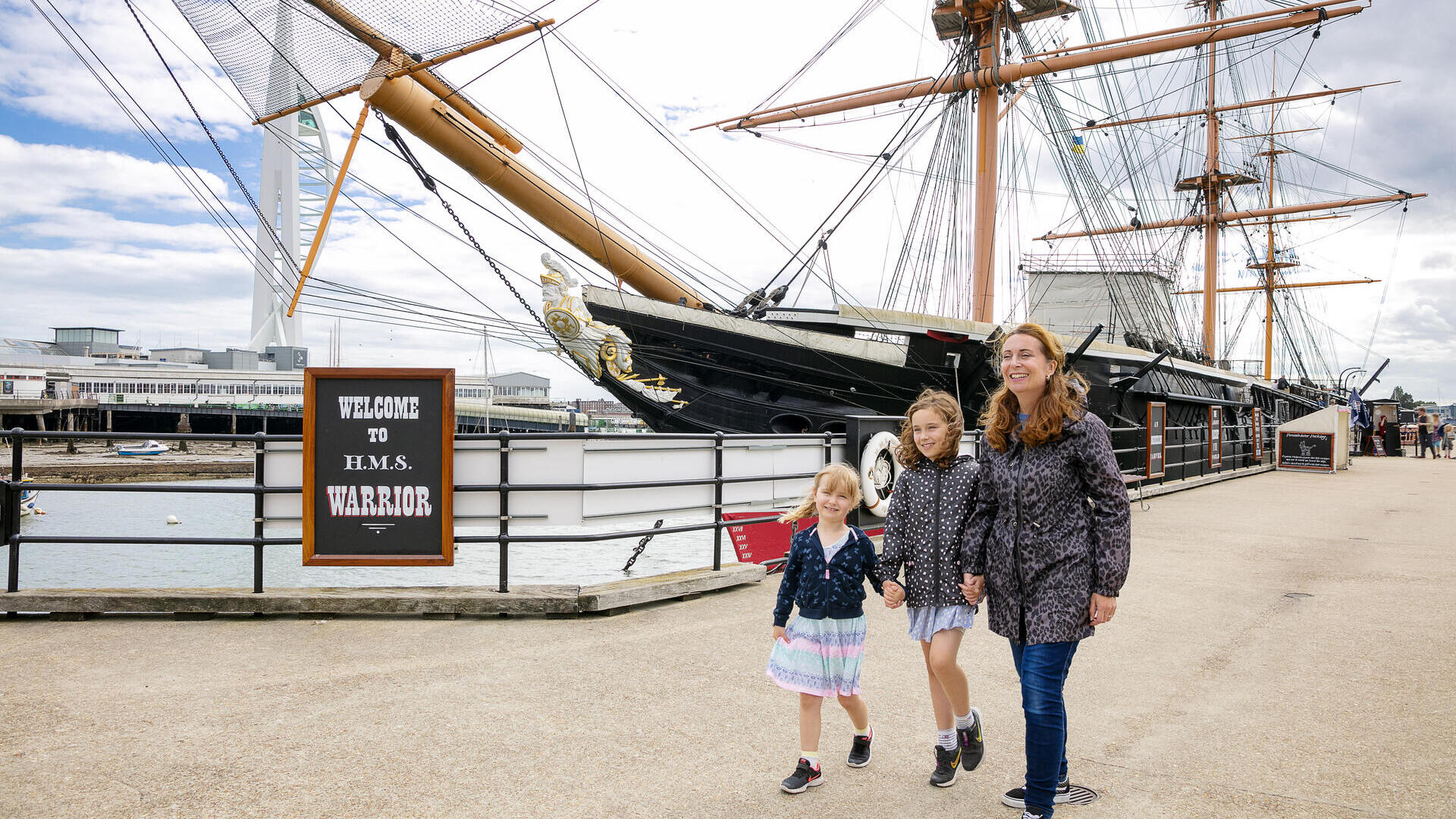 A family walking alongside a ship at a dock
