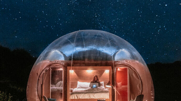 Vrouw in een bed in een glamping-bubbelpod 's nachts