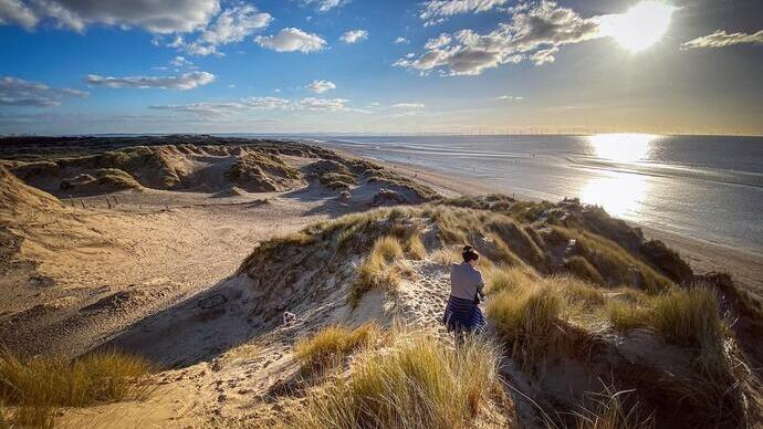 Woman walking along sand dunes at Formby beach